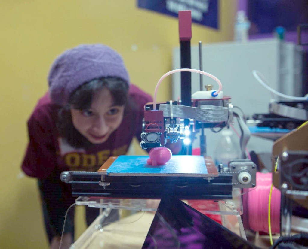 A student watches her 3D printed art come to life.